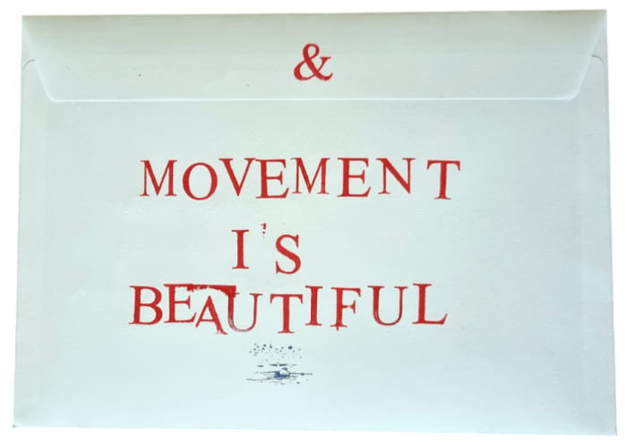 Ein weisser Briefumschlag mit rotem Text, auf dem steht: -- MOVEMENT I'S BEAUTIFUL -- und ein --&--  Symbol oben. Postkarte Mail Art Arte Postale
